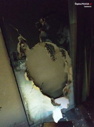 Drzwi wejściowe do mieszkania, w którym wybuchł pożar z wybitym otworem, dzięki któremu policjanci dostali się do środka lokalu