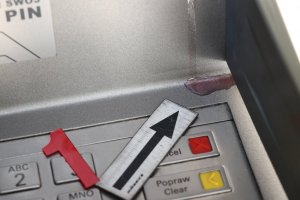 Zdjęcie przedstawia panel bankomatu z widoczną plamą koloru czerwonego