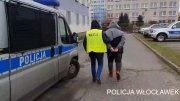 policjant kryminalny w kamizelce z napisem Policja prowadzi zatrzymanego