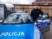 policjant Wydziału Ruchu Drogowego Komendy Powiatowej Policji w Mońkach stoi przy radiowozie