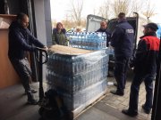 policjanci oraz inne osoby pomagają przenieść palety z wodą