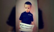 mały chłopiec w stroju policjanta trzyma kartkę z napisem nie okłamuj policjanta