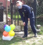 Policjantka pozostawiająca tort i balony pod furtką