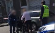 Policjanci pomagają kobiecie w ciąży usiąść na wózek pod szpitalem