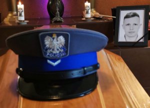 czapka zmarłego policjanta leżąca na trumnie, w tle jego zdjęcia