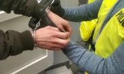 policjant zakłada zatrzymanemu kajdanki