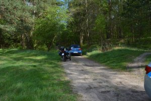 auto, którym uciekał kierujący i policyjny motocykl na leśnej drodze