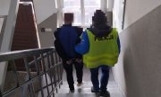 Policjant z zatrzymanym na schodach komendy