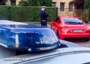 Kogut policyjny w tle policjant stoi przy samochodzie