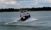 dwaj policjanci podczas patrolu płyną na łodzi policyjnej