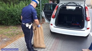 Policjant przenosi worek w bezpieczne miejsce