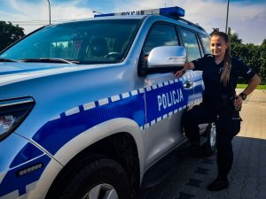 Umundurowana policjantka stoi obok radiowozu