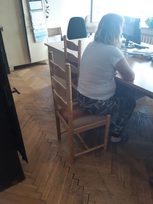 zatrzymana kobieta w trakcie przesłuchania siedzi przy biurku na krześle