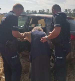 Policjanci podtrzymują starsza kobietę