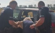 Policjanci podtrzymują starsza kobietę