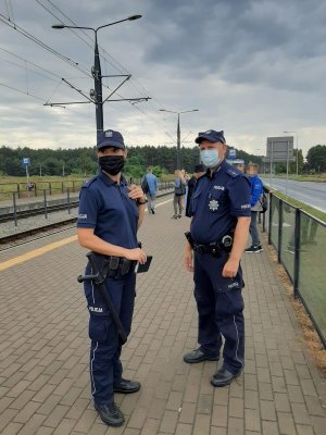 policjanci stoją na przystanku tramwajowym w ramach sprawdzenia obowiązku zakrywania ust i nosa w komunikacji publicznej