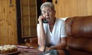 starsza kobieta siedzi na kanapie i rozmawia przez telefon