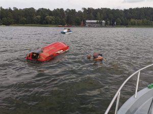 wywrócony skuter na jeziorze i policjant ratujący jednego z mężczyzn
