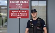 policjant stoi na tle budynku Komendy Miejskiej Policji w Kaliszu