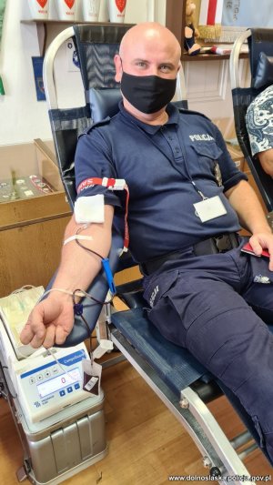 Policjant siedzący na specjalistycznym fotelu podczas oddawania krwi.