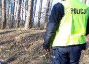 policjant  w lesie w kamizelce z napisem: Policja