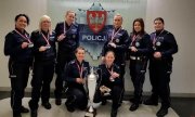 Drużyna Wielkopolskiej Policji Kobiet w Piłce Nożnej na tle loga policji wielkopolskiej