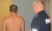 Policjant sprawdza mężczyznę przed celą