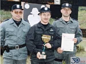 Trzej funkcjonariusze prezentujący zdobyte trofea na zawodach strzeleckich - zdjęcie historyczne.