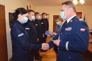 Policjantka odbiera legitymację służbową z rąk Komendanta Wojewódzkiego Policji w Rzeszowie nadinspektora Henryka Moskwy. Wszyscy uczestnicy uroczystości w maseczkach