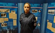 starsza sierżant Karoliny Kurpisz stoi na tle wystawy na temat historii Policji