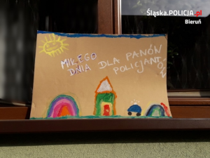 Wystawiony na parapet okna dziecięcy rysunek, na którym widnieje napis: &quot;MIŁEGO DNIA DLA PANÓW POLICJANTÓW&quot;