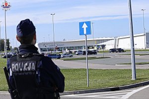 Stojący tyłem policjant, w tle widać lotnisko