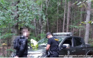 policjant obok samochodu straży leśnej wypisuje mandat stojącemu obok kierowcy motocykla