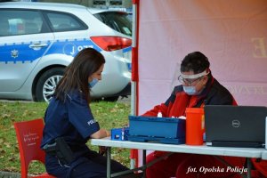 Sanitariusz kwalifikujący policjantkę do oddania krwi (oboje w maseczkach)