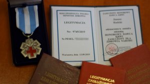 Medal i książeczki potwierdzające otrzymanie medalu przez policjanta Janusza Rudzkiego.&quot;&gt;