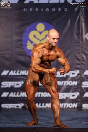 Sierżant sztabowy Marcin Dziadczyk stojący przodem pochylony i prezentujący bicepsy