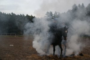 dwaj policyjni jeźdźcy na koniach przejeżdżają przez tumany dymu z palącej się sterty siana