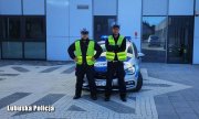 Dwaj umundurowani policjanci ruchu drogowego stoją przed radiowozem