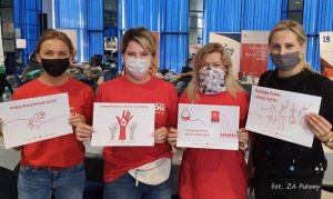 Cztery kobiety w maseczkach trzymające kartki zachęcające do udziału w akcjach krwiodawstwa