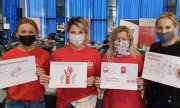 Cztery kobiety w maseczkach trzymające kartki zachęcające do udziału w akcjach krwiodawstwa