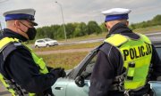 Umundurowani policjanci podczas kontroli drogowej stoją przy samochodzie