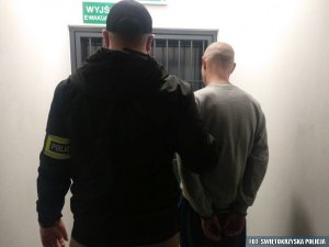 nieumundurowany policjant z zatrzymanym stoją przed pomieszczeniem dla osób zatrzymanych