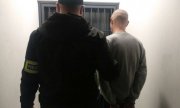 nieumundurowany policjant z zatrzymanym stoją przed pomieszczeniem dla osób zatrzymanych