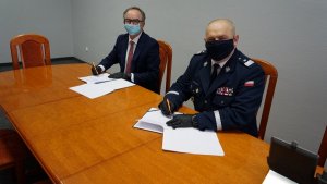 Komendant Wojewódzki podpisuje porozumienie z prezesem Lotosu siedząc przy stole
