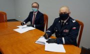 Komendant Wojewódzki podpisuje porozumienie z prezesem Lotosu, obaj siedzą przy stole