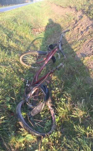 Zniszczony w wyniku wypadku czerwony rower leżący w rowie