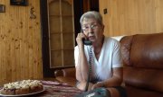 Starsza kobieta siedzi na kanapie i rozmawia przez telefon