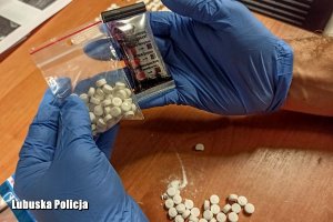 tabletki ecstasy leżące na stole i w woreczku trzymanym w dłoniach, na które założone są rękawiczki