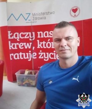 Na zdjęciu aspirant sztabowy Radosław Dobosz na tle baneru z hasłem Łączy nas krew, która ratuje życie.