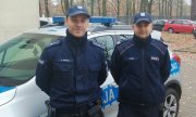 młodszy aspirant Piotr Iwaniuk i sierżant sztabowy Adam Skubik w tle radiowóz policyjny